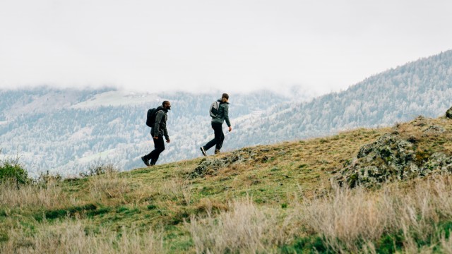 Vrouw in zomerse outdoor-kleding balanceert op stenen bij een meer