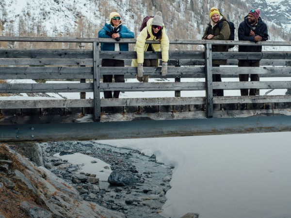 Vier vrienden genieten van het uitzicht vanaf een houten brug in een besneeuwd landschap
