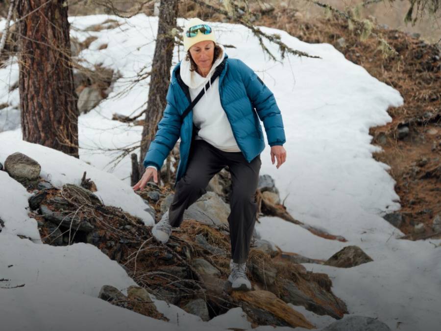 Deux luges transportant chacune deux personnes descendent une piste enneigée. Les personnes rient et portent des vêtements d’hiver, des bonnets et des lunettes de soleil ; en arrière-plan, des montagnes enneigées.