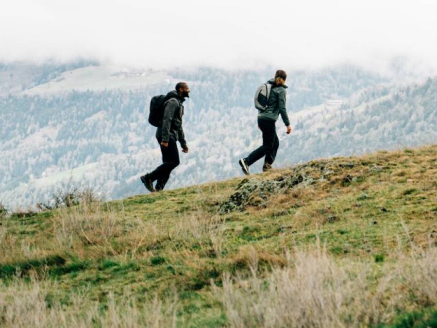 Quatre personnes en tenue de randonnée estivale courent à travers un champ