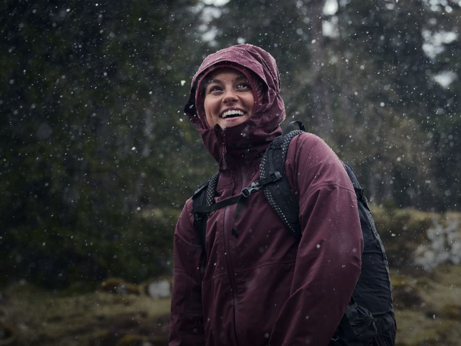 Une femme avec un imperméable sous la pluie dans la forêt
