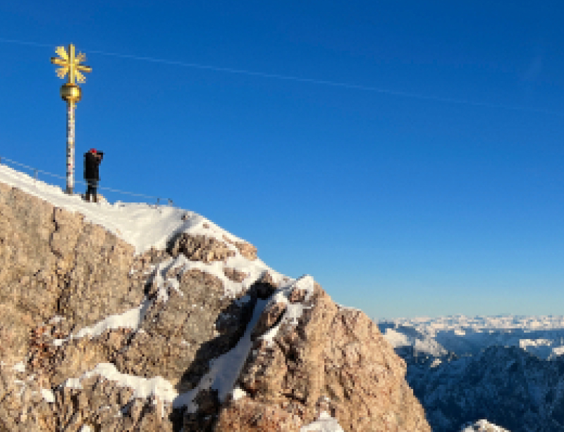 Yuto bij een kruis op een bergtop in de sneeuw