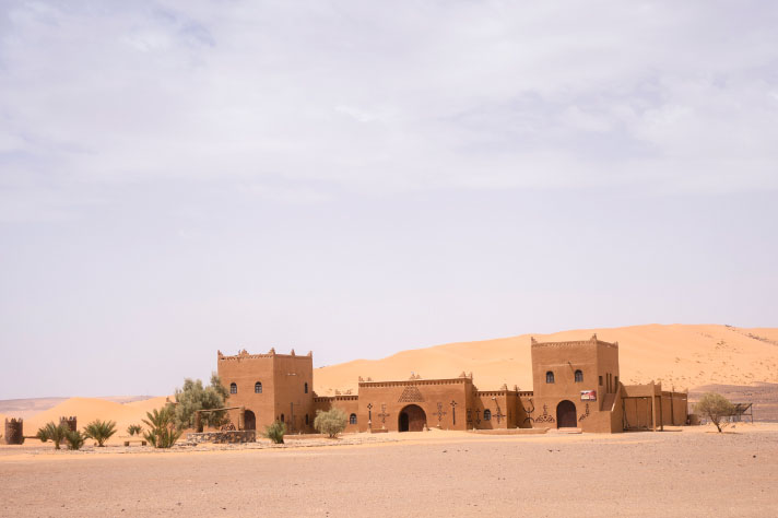 Bruin gebouw met palmen in een woestijn