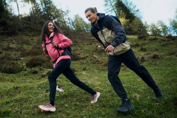 Un homme et une femme en tenue de randonnée sportive traversent une clairière