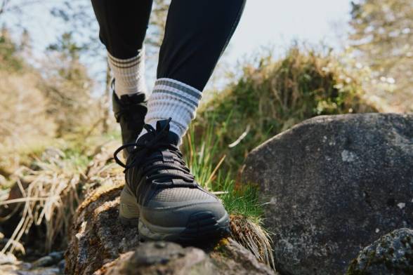 Gros plan d’une personnes en chaussures de randonnée marchant sur un rocher