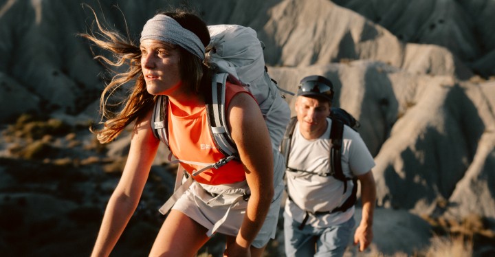 Vrouw en man in zomerse wandelkleding bij zonsondergang